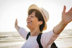 Happy senior woman with arms up having fun on the beach.  Emotional Difficulties of Change.  Embracing Change