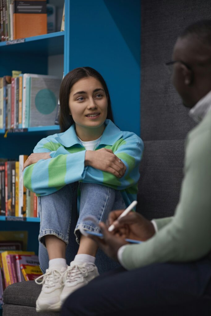 Stressed teenage girl talking to mental health therapist in college library. Comprehensive Mental Health and Forensic Services